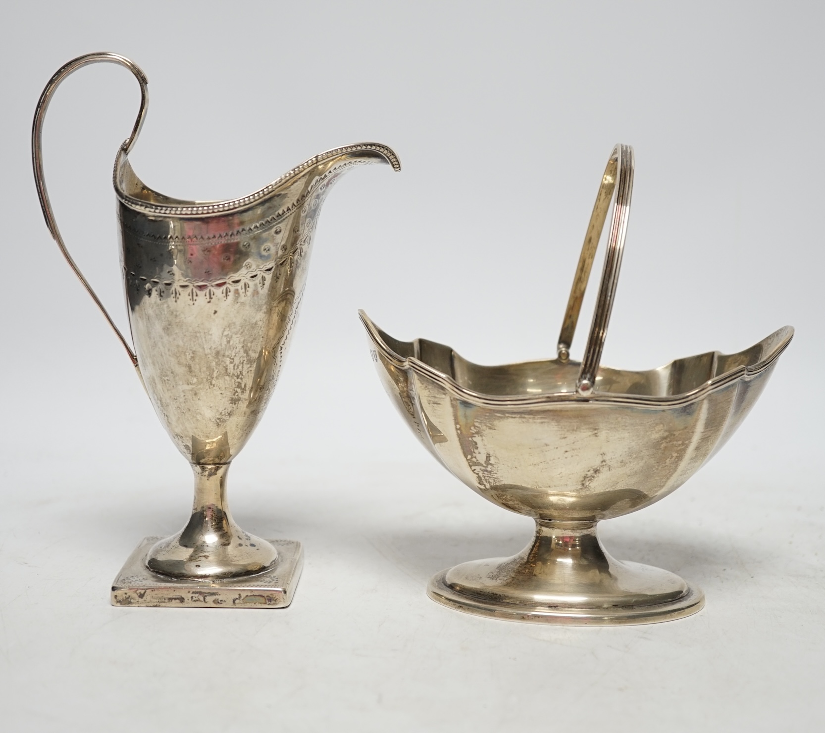 A late Victorian silver oval sugar basket, by Thomas Bradbury & Sons, London, 1894, height length 13.5cm (fair condition), together with a George III silver cream jug, marks rubbed, 8.5oz, (poor condition).